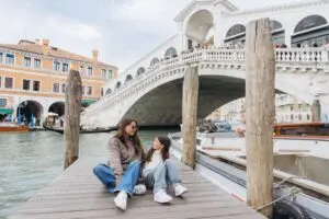 Mother and daughter on a wooden pier by Rialto Bridge during a family trip to Venice Italy