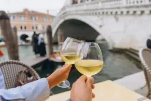 Couple toasting white wine by the Rialto Bridge on a romantic private Italy tour in Venice
