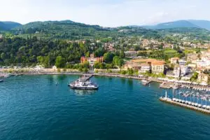 Ferry arriving at Garda harbor on Lake Garda with passengers and hillside town scenery in Italy
