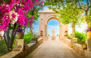 Villa Cimbrone Gardens in Ravello, Italy with flowering bougainvillea, stone archway, statue, and Amalfi Coast views