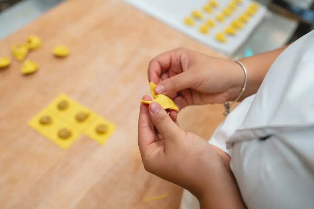 Hands shaping fresh homemade tortellini pasta during an Italian cooking class culinary tour in Italy