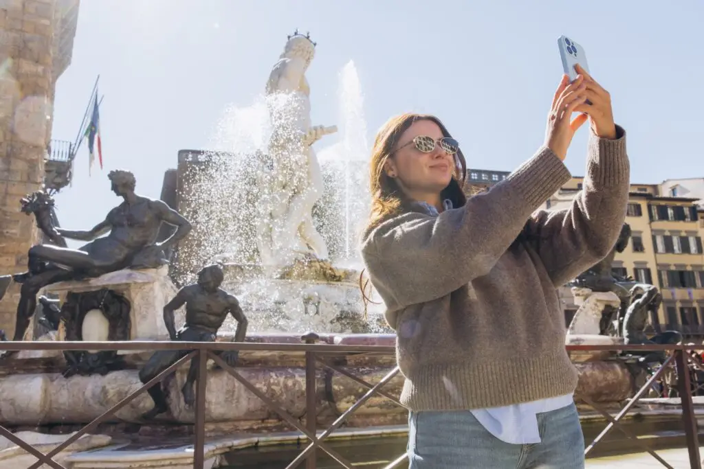 Young woman taking a travel selfie at the Fountain of Neptune in Florence, Italy on a private Italy tour
