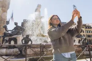 Young woman taking a travel selfie at the Fountain of Neptune in Florence, Italy on a private Italy tour
