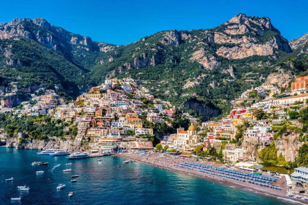 Aerial view of Positano on the Amalfi Coast in Italy with colorful cliffside houses, beach umbrellas, boats and blue sea