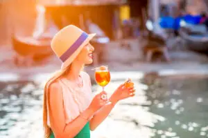 Young woman enjoying Aperol Spritz and Italian snacks by a canal in Italy on a private Italy tour