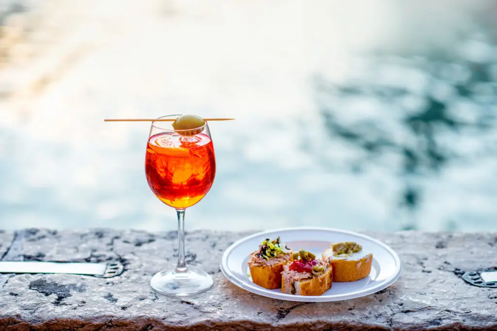 Aperol Spritz with Venetian cicchetti snacks overlooking a canal in Venice, Italy