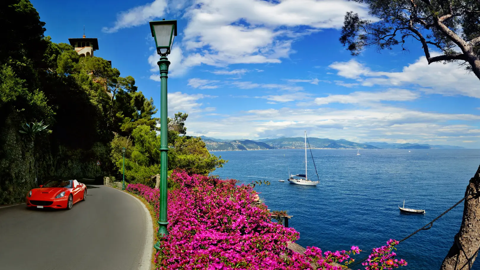 Panoramic view of the Italian Riviera from the scenic coastal road to Portofino, Italy, with sailboats and flowers overlooking the Ligurian Sea