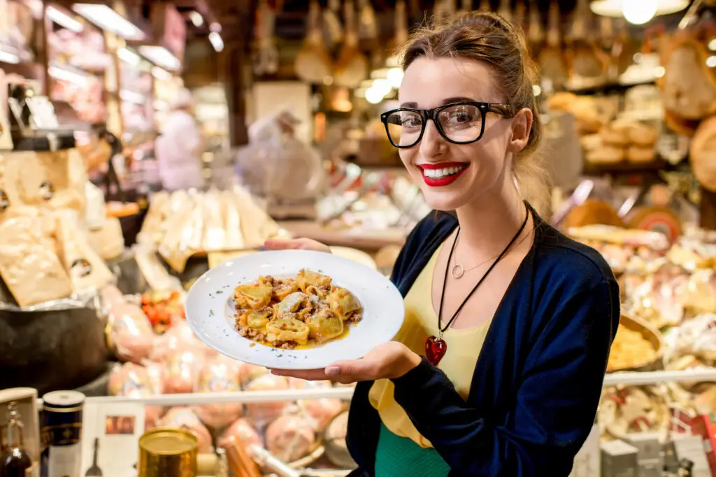 Young woman holding traditional Italian tortellini pasta in a food shop during an Italy food tour
